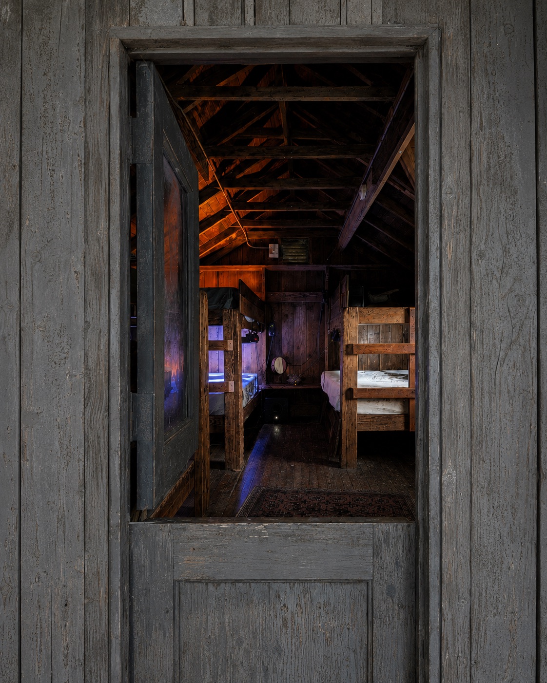 a view through the cabin door into the lit bunk room