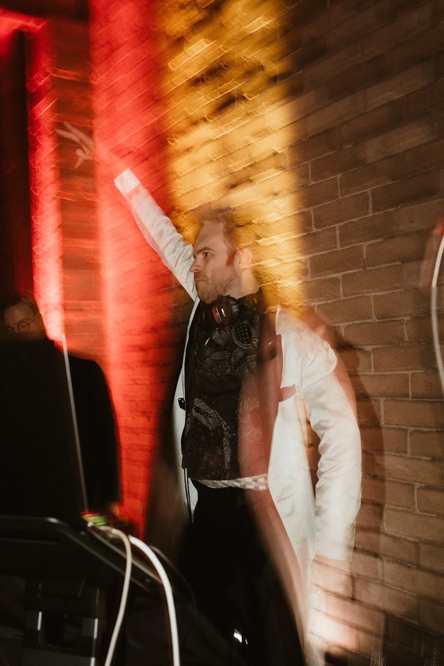 the groom&rsquo;s debut set, arm raised under red light